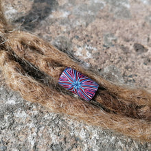 Colorful bead on a dreadlock against a stone background