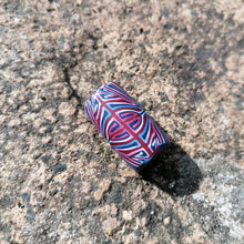 Colorful cylindrical object with a geometric pattern on a textured stone surface