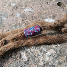 Multicolored bead on a dreadlock against a stone background
